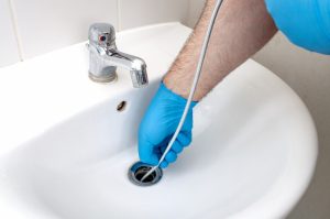 gloved-hands-working-on-a-clogged-bathroom-sink